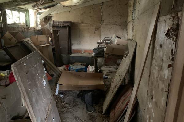 Débarras d'un hangar, pièce pleine de bois et cartons, déchets divers et sale avant